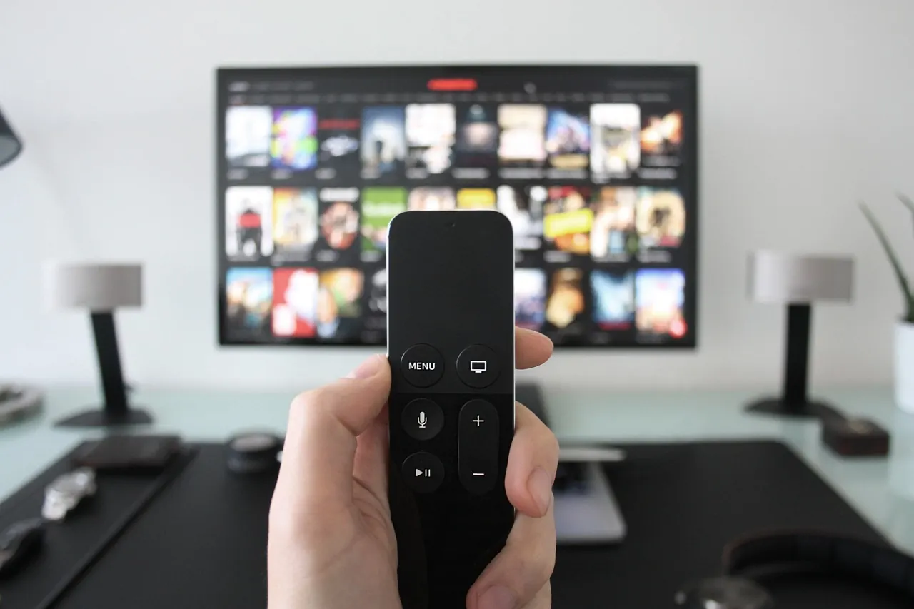 Stock photo: Hand holding remote control towards television screen