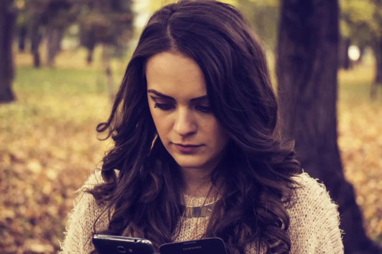 Foto de archivo: persona triste mirando el teléfono móvil