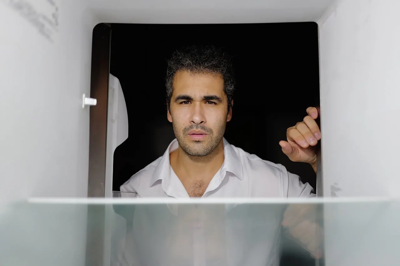 Foto de archivo: hombre mirando la nevera abierta pensativo