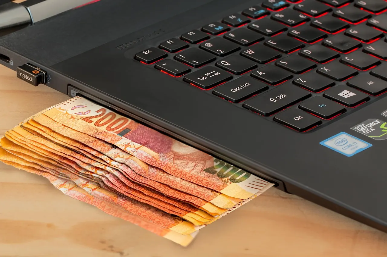 Fotografie de arhivă: bani sub saltea lângă un laptop deschis