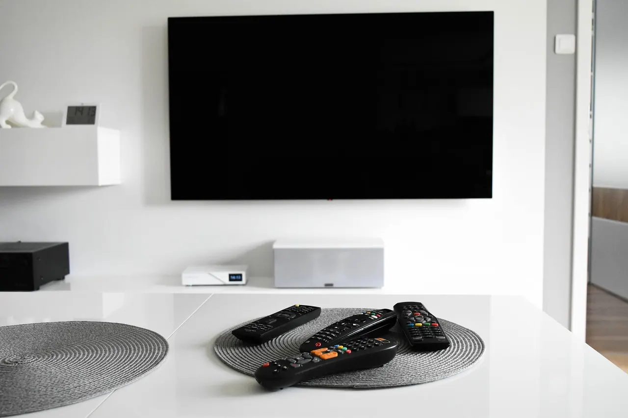 Stock photo: person holding remote control facing multiple television screens