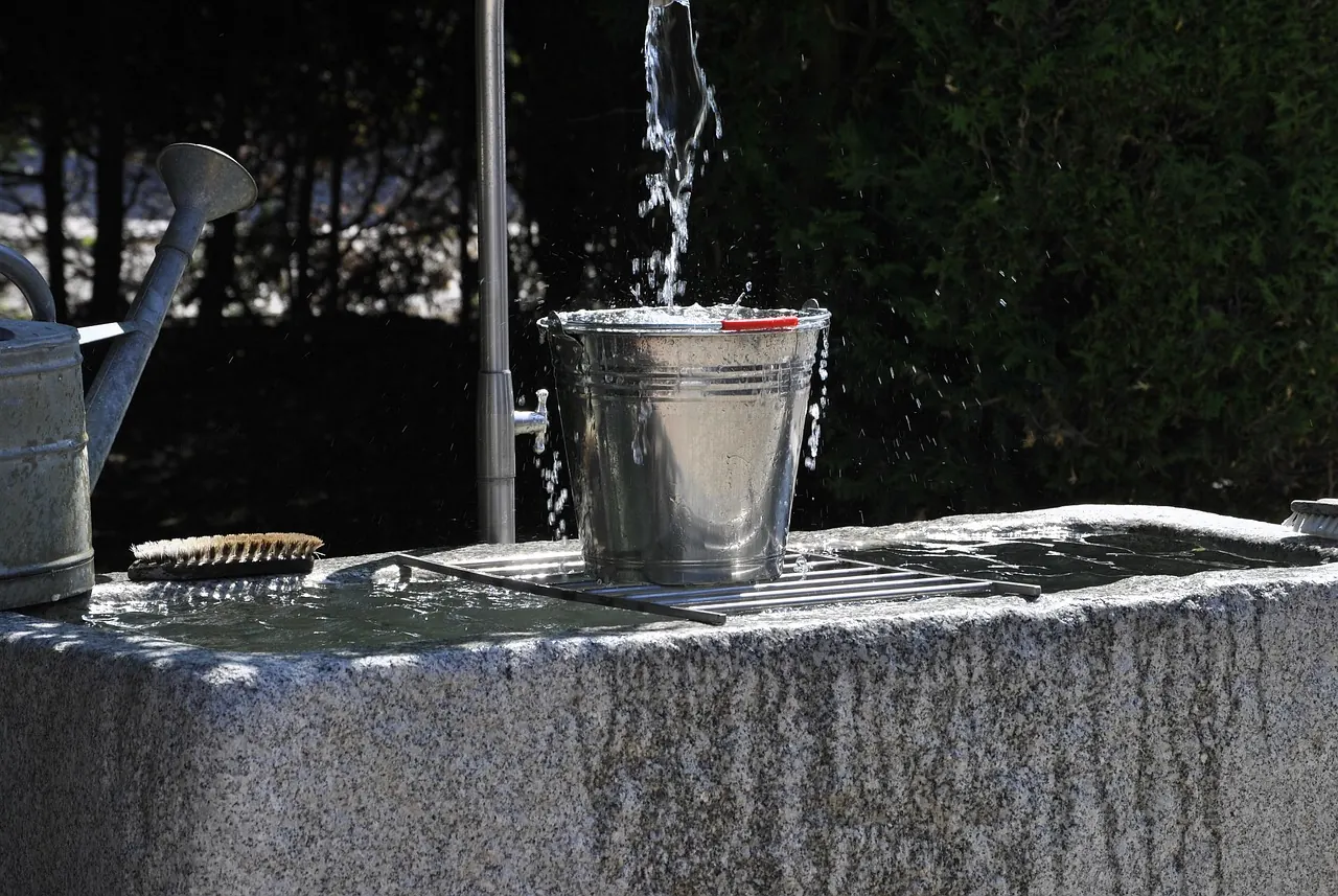 Stock photo: water leaking from pipe into full bucket